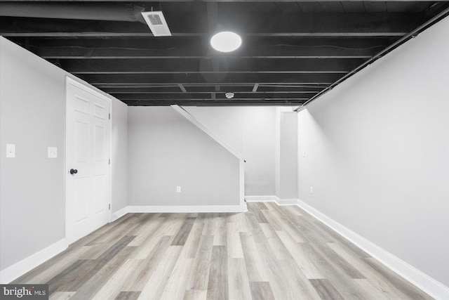 finished below grade area with light wood-style floors and baseboards