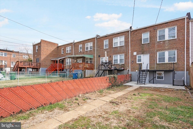 rear view of property with central AC, brick siding, and fence