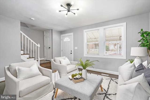 living room with wood finished floors, visible vents, baseboards, and stairs