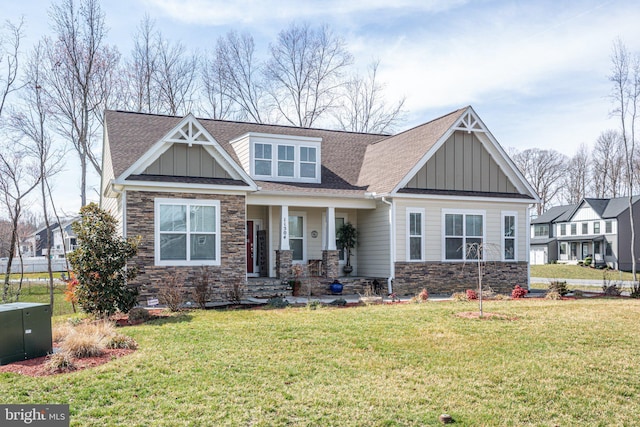 craftsman house featuring stone siding, board and batten siding, a front yard, and a shingled roof