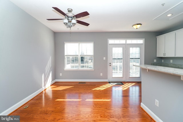 interior space with light wood-type flooring, a ceiling fan, and baseboards