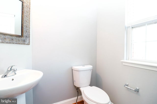 bathroom with a sink, toilet, and baseboards