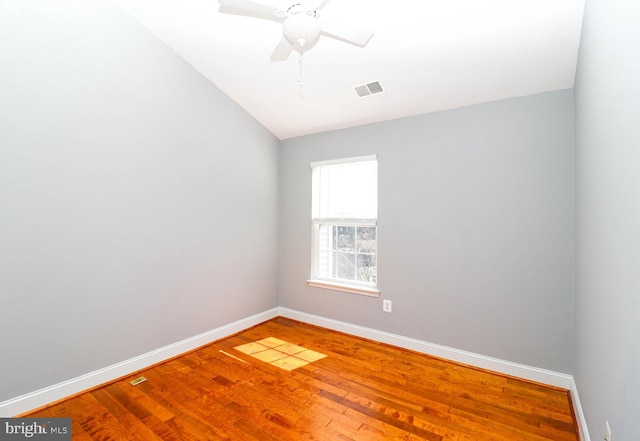 spare room featuring a ceiling fan, baseboards, visible vents, and wood finished floors