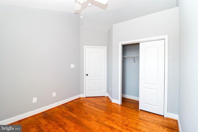 unfurnished bedroom featuring a closet, wood finished floors, a ceiling fan, and baseboards