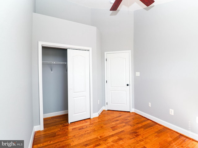 unfurnished bedroom featuring a ceiling fan, a closet, baseboards, and wood finished floors