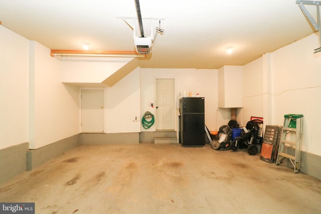 garage featuring freestanding refrigerator and a garage door opener