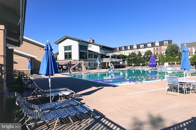 pool with a water slide, a patio area, and fence