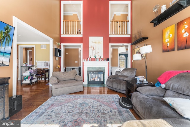 living room featuring visible vents, a high ceiling, wood finished floors, and a high end fireplace