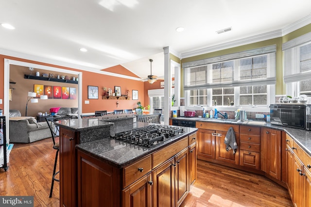 kitchen featuring a kitchen bar, visible vents, light wood-style flooring, and gas cooktop