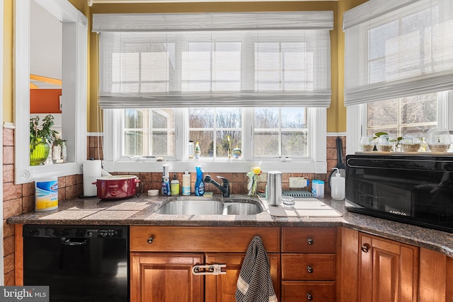 kitchen with brown cabinets, a sink, black dishwasher, dark countertops, and a toaster