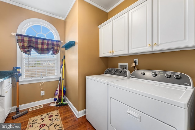 washroom with visible vents, crown molding, dark wood-type flooring, washer and clothes dryer, and cabinet space