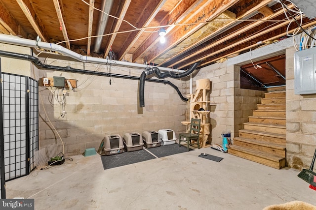 unfinished basement featuring electric panel and stairs