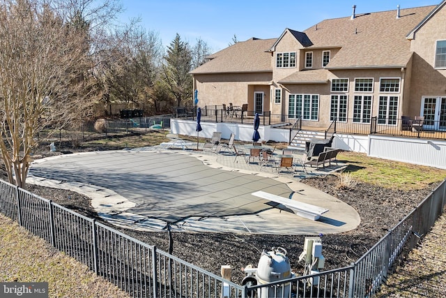 rear view of property featuring a patio area, stucco siding, fence private yard, and a fenced in pool