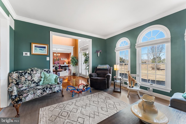 living room with wood finished floors, a chandelier, baseboards, and ornamental molding