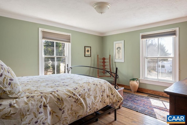 bedroom featuring visible vents, ornamental molding, a textured ceiling, and wood-type flooring