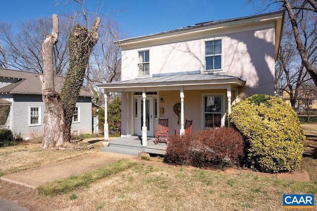 view of front of home with covered porch, metal roof, a standing seam roof, and stucco siding