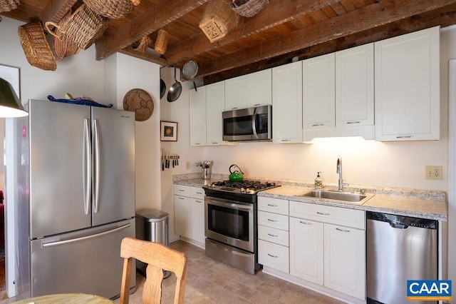 kitchen featuring white cabinetry, beam ceiling, appliances with stainless steel finishes, and a sink