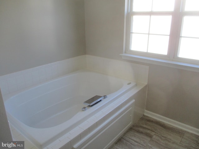 bathroom with a bath and baseboards