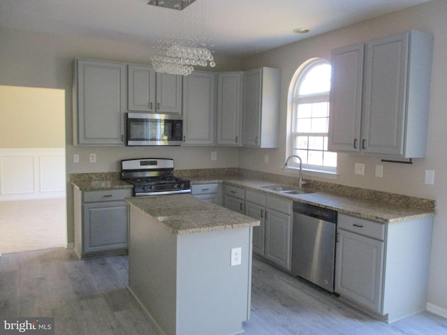 kitchen with a center island, gray cabinetry, appliances with stainless steel finishes, light wood-style floors, and a sink