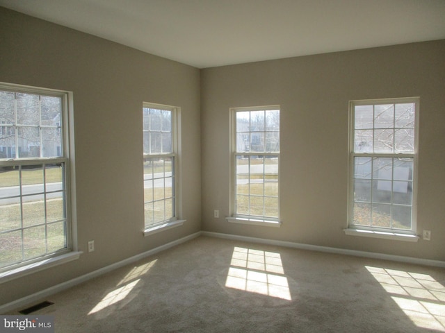 carpeted spare room featuring visible vents and baseboards