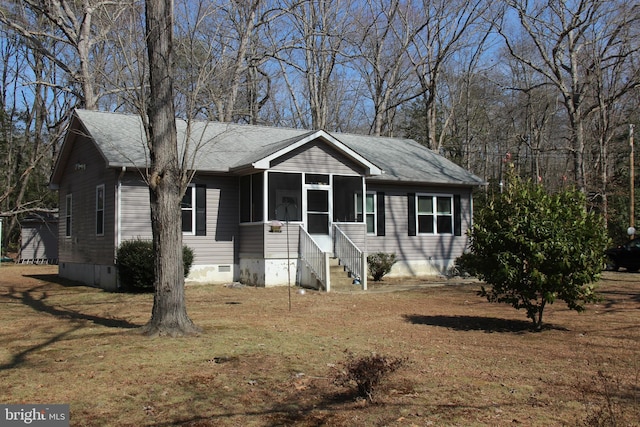 view of front of home featuring crawl space, a shingled roof, a front lawn, and a sunroom