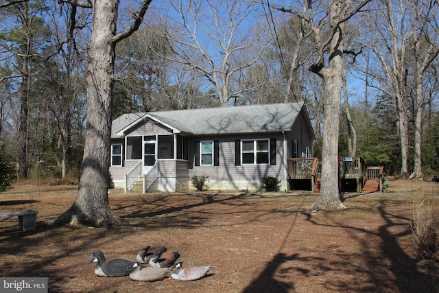 view of front of property featuring a wooden deck, a shingled roof, and a sunroom