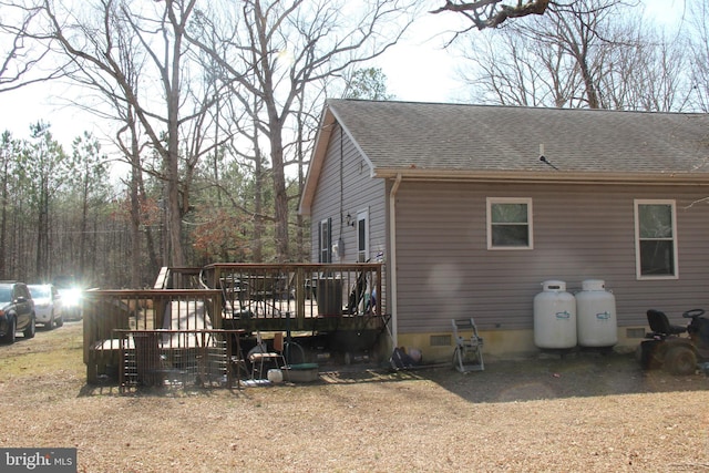 view of side of home with crawl space, roof with shingles, and a wooden deck