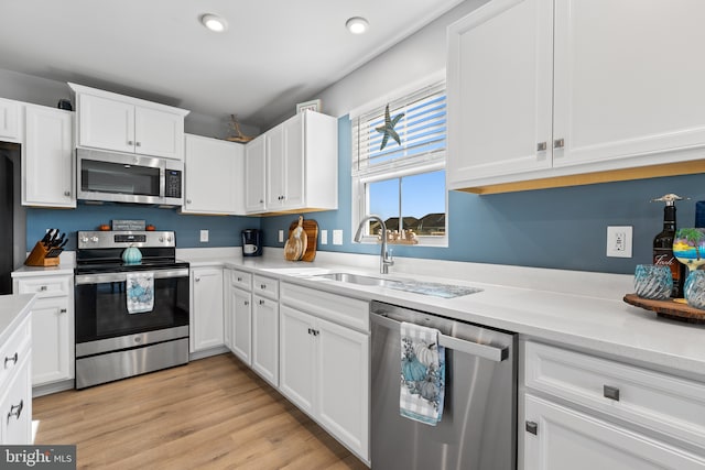 kitchen with white cabinetry, stainless steel appliances, a sink, and light countertops