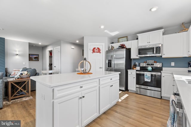 kitchen with appliances with stainless steel finishes, light wood-type flooring, a kitchen island, and recessed lighting