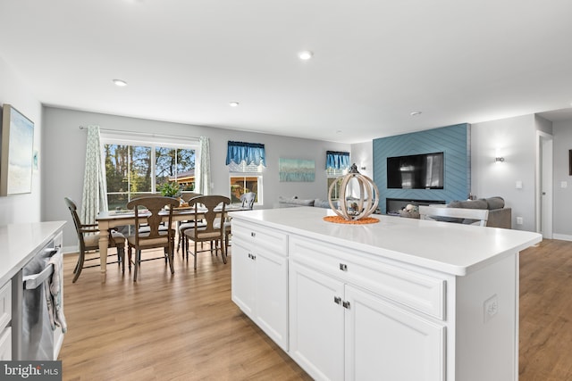 kitchen with light wood-style floors, white cabinetry, stainless steel dishwasher, and a wealth of natural light