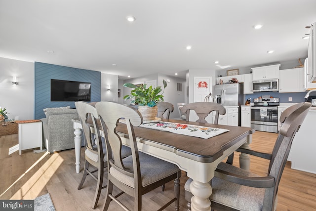 dining area featuring an accent wall, recessed lighting, and light wood-style floors