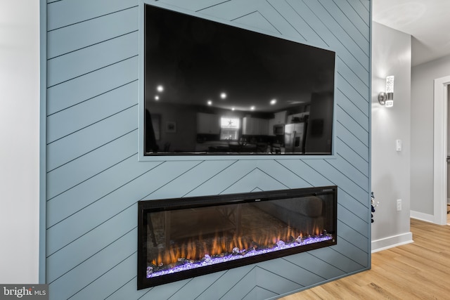 interior details featuring a large fireplace, baseboards, and wood finished floors