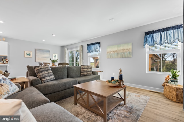 living area with light wood finished floors, visible vents, baseboards, and recessed lighting