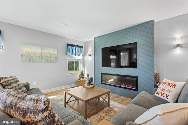 living area with a large fireplace, wood finished floors, and baseboards