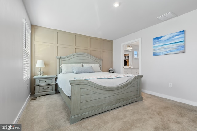 bedroom featuring light carpet, baseboards, visible vents, and connected bathroom