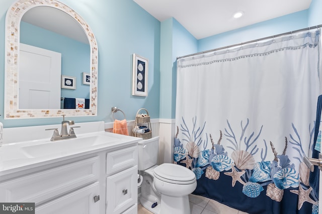 full bath with tile patterned flooring, a wainscoted wall, vanity, and toilet