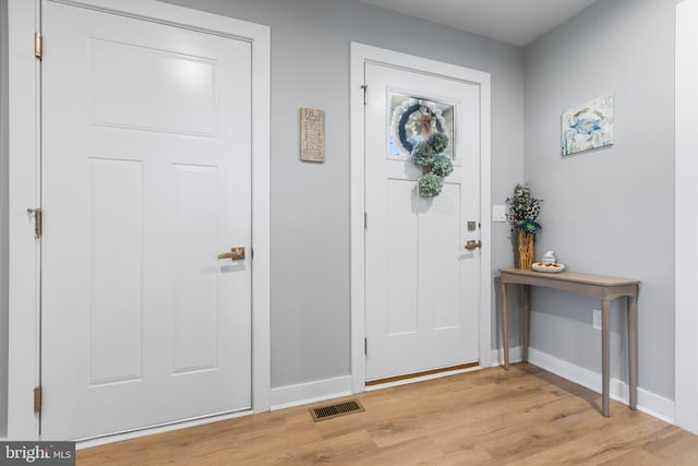 entryway with light wood finished floors, baseboards, and visible vents