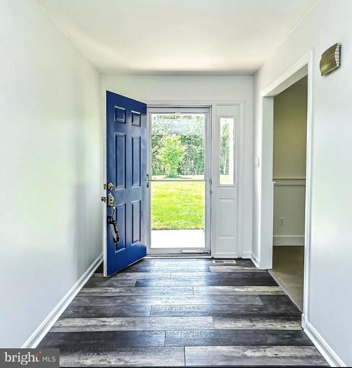 foyer featuring dark wood-type flooring and baseboards