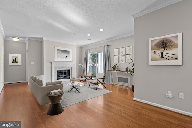 living room with ornamental molding, a high end fireplace, a textured ceiling, wood finished floors, and baseboards