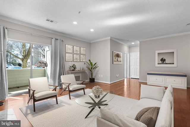 living room featuring ornamental molding, visible vents, baseboards, and wood finished floors