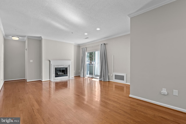 unfurnished living room with visible vents, ornamental molding, a high end fireplace, wood finished floors, and baseboards