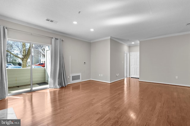 spare room with ornamental molding, wood finished floors, visible vents, and baseboards