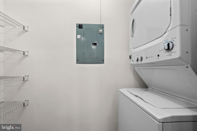 washroom featuring stacked washing maching and dryer, electric panel, and laundry area