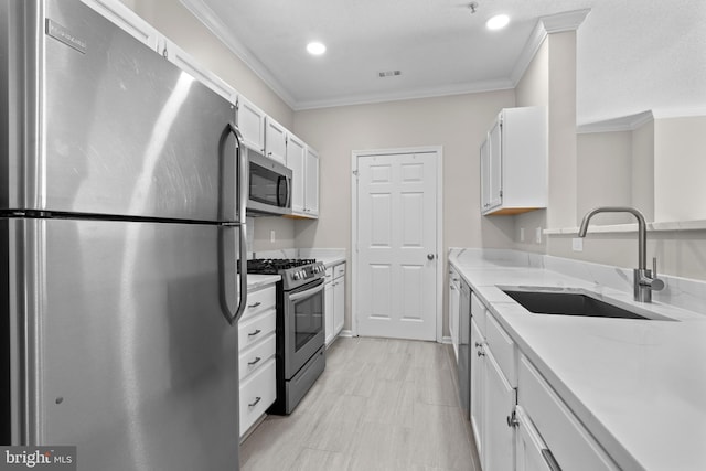 kitchen with stainless steel appliances, white cabinetry, a sink, and ornamental molding