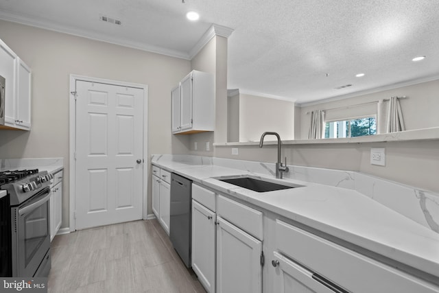 kitchen featuring visible vents, white cabinets, ornamental molding, stainless steel appliances, and a sink