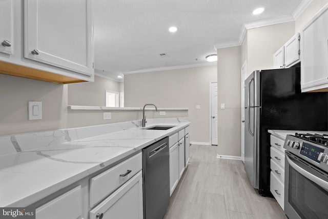 kitchen with white cabinets, appliances with stainless steel finishes, light stone countertops, crown molding, and a sink