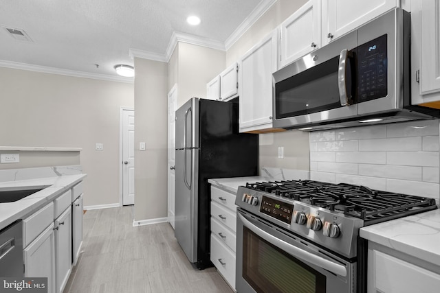 kitchen with appliances with stainless steel finishes, visible vents, ornamental molding, and white cabinetry