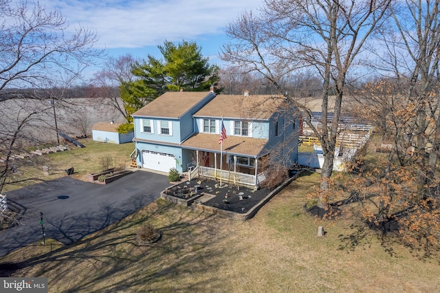 traditional home with a front yard, a garage, covered porch, and driveway