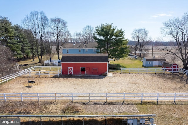 exterior space featuring an outbuilding, a rural view, a barn, and fence