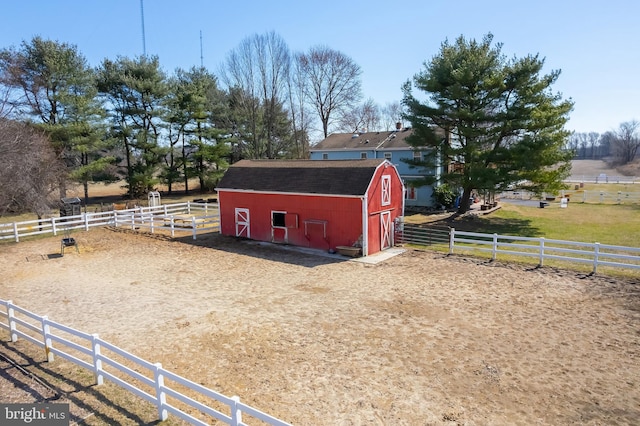 view of barn with a rural view and fence